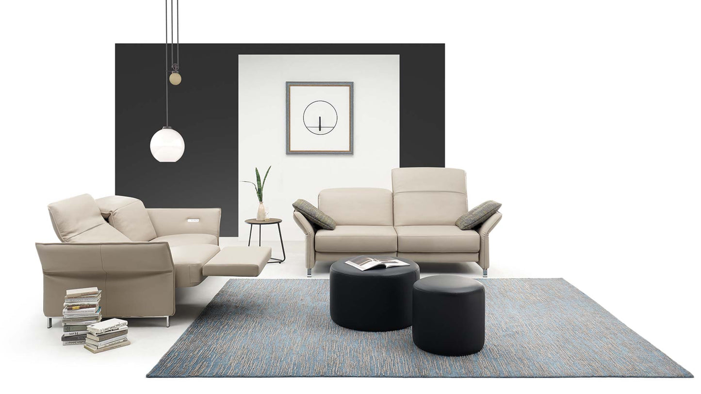 Elektrisch verstellbares Sofa in beigem Leder mit Schlaffunktion, Armlehnen- und Rückenverstellung in einem hellen Wohnzimmer.