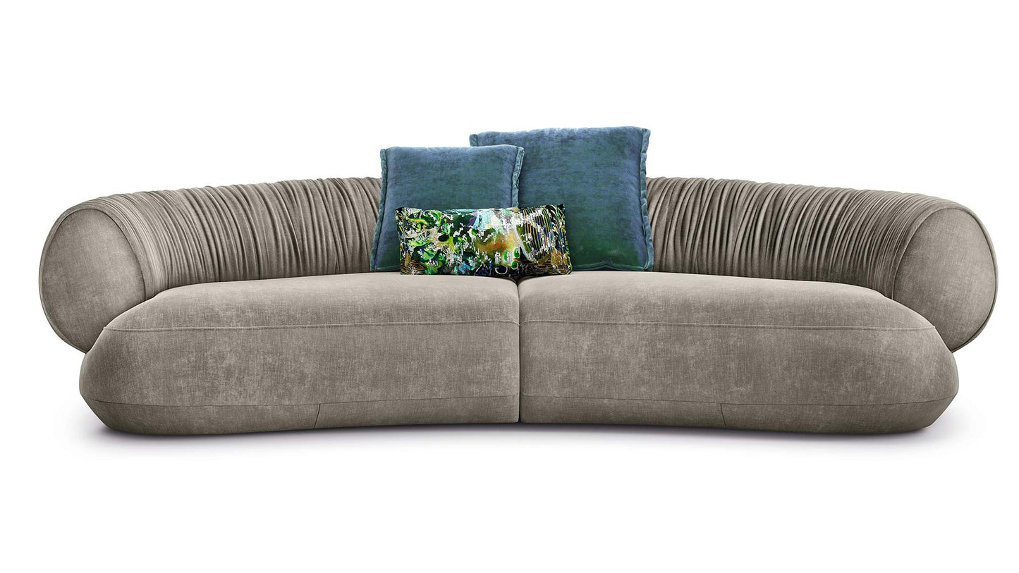 Bretz Couch Nanami in einem grau-beigen Velours mit blauen Verlourskissen.
