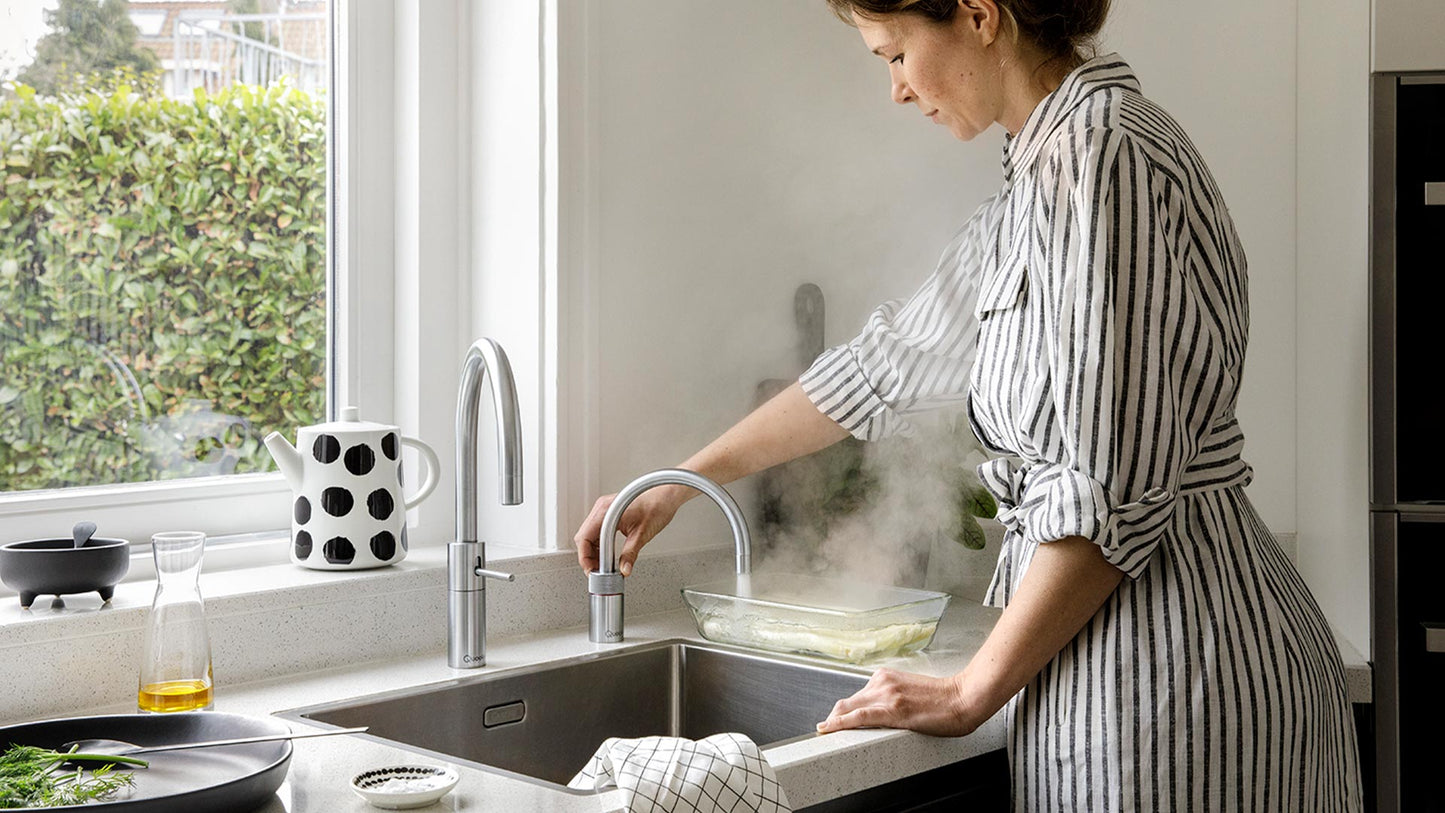 Gräuliche Küchenzeile mit zwei Kuka Wasserhähne in Voll-Edelstahl und rundem Auslauf mit Heißwasser.