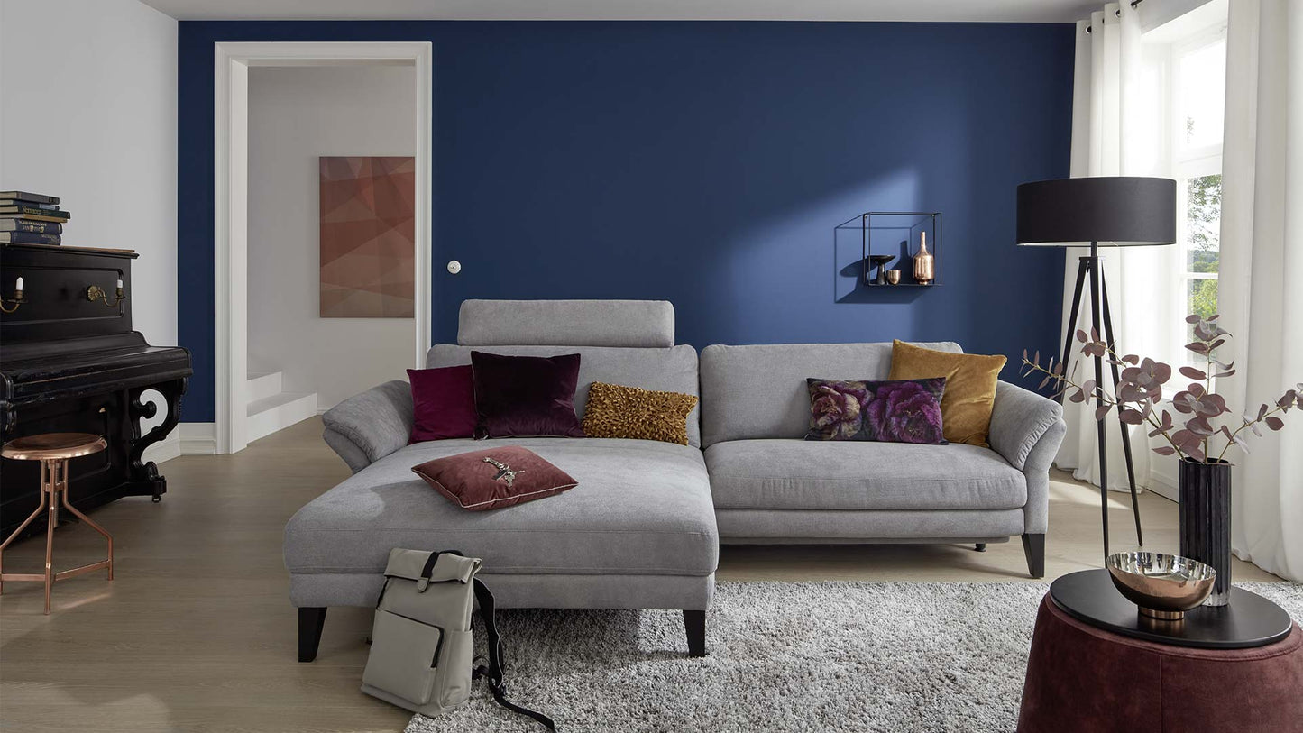 Blaues Wohnzimmer mit grauem Funktionssofa mit Relaxfunktion und schwarzen Holzfüßen.