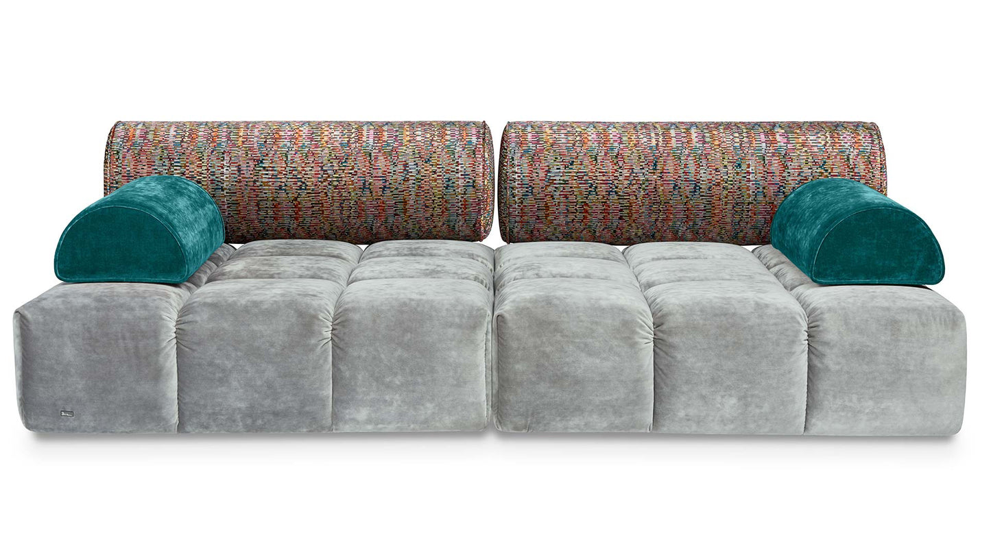 Ed Couch von Bretz silbernem Velours und bunt gemusterten Polsterrollen und blauen Plaidkissen in Velours.