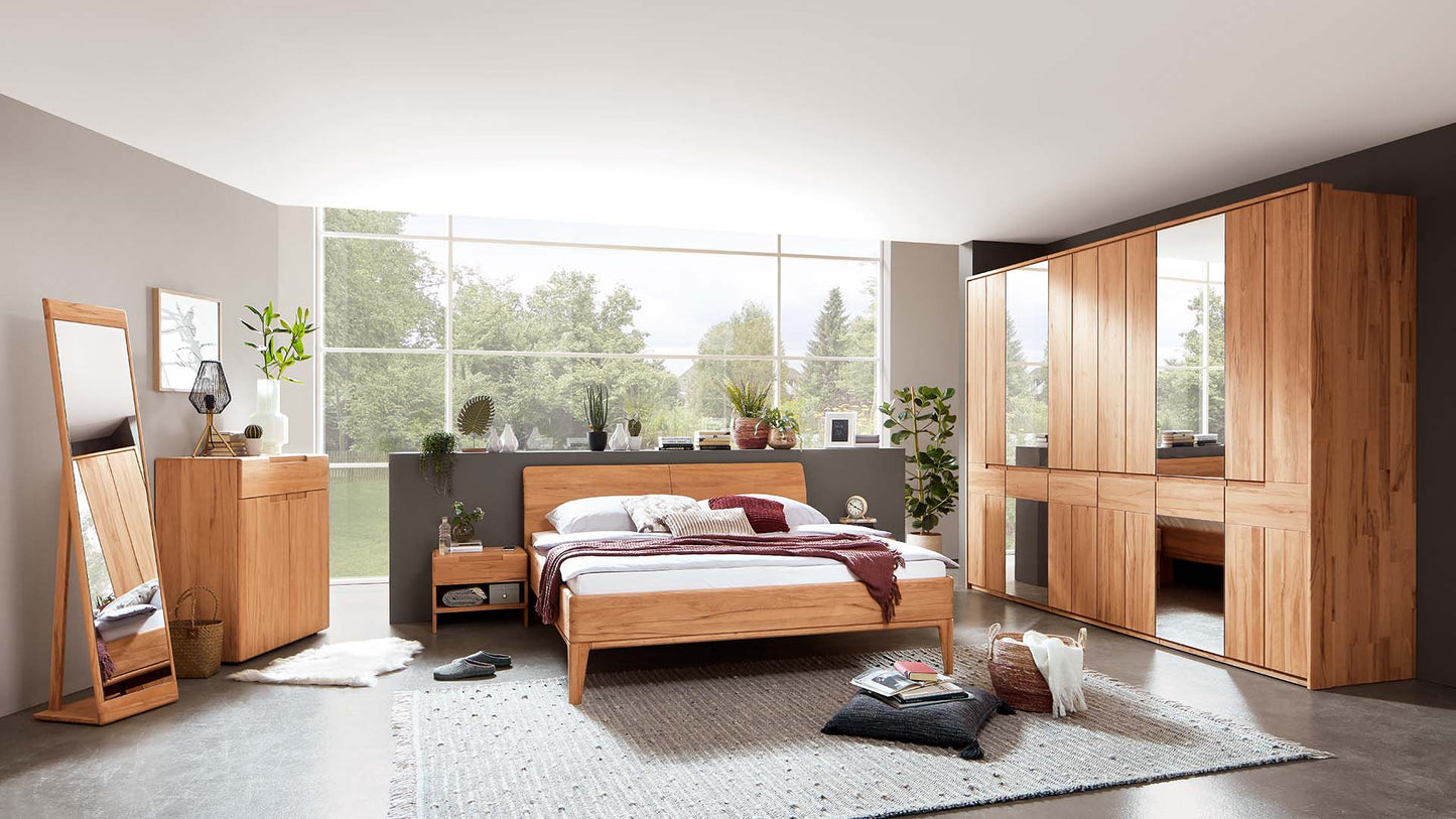 Helles Schlafzimmer mit Schlafzimmersystem in Kernbuche mit Naturholzbett, Nachttisch, Kleiderschrank mit Spiegelfront, Kommode und Standspiegel.