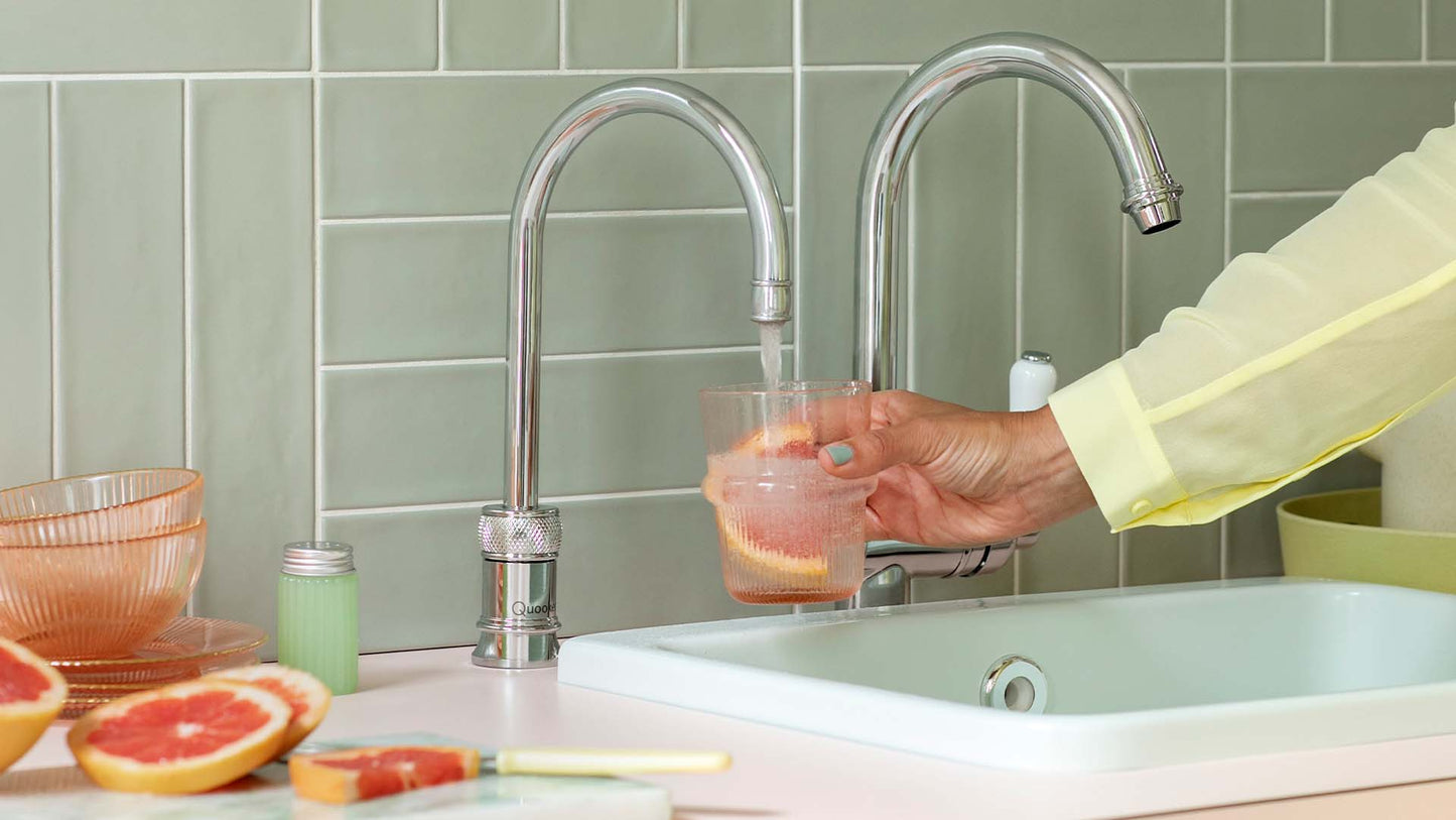 Helle, salbeifarbene Küchenzeile mit Wasserhahn mit kochendem Wasser im klassischen Design in verchromt glänzend und rundem Auslauf.