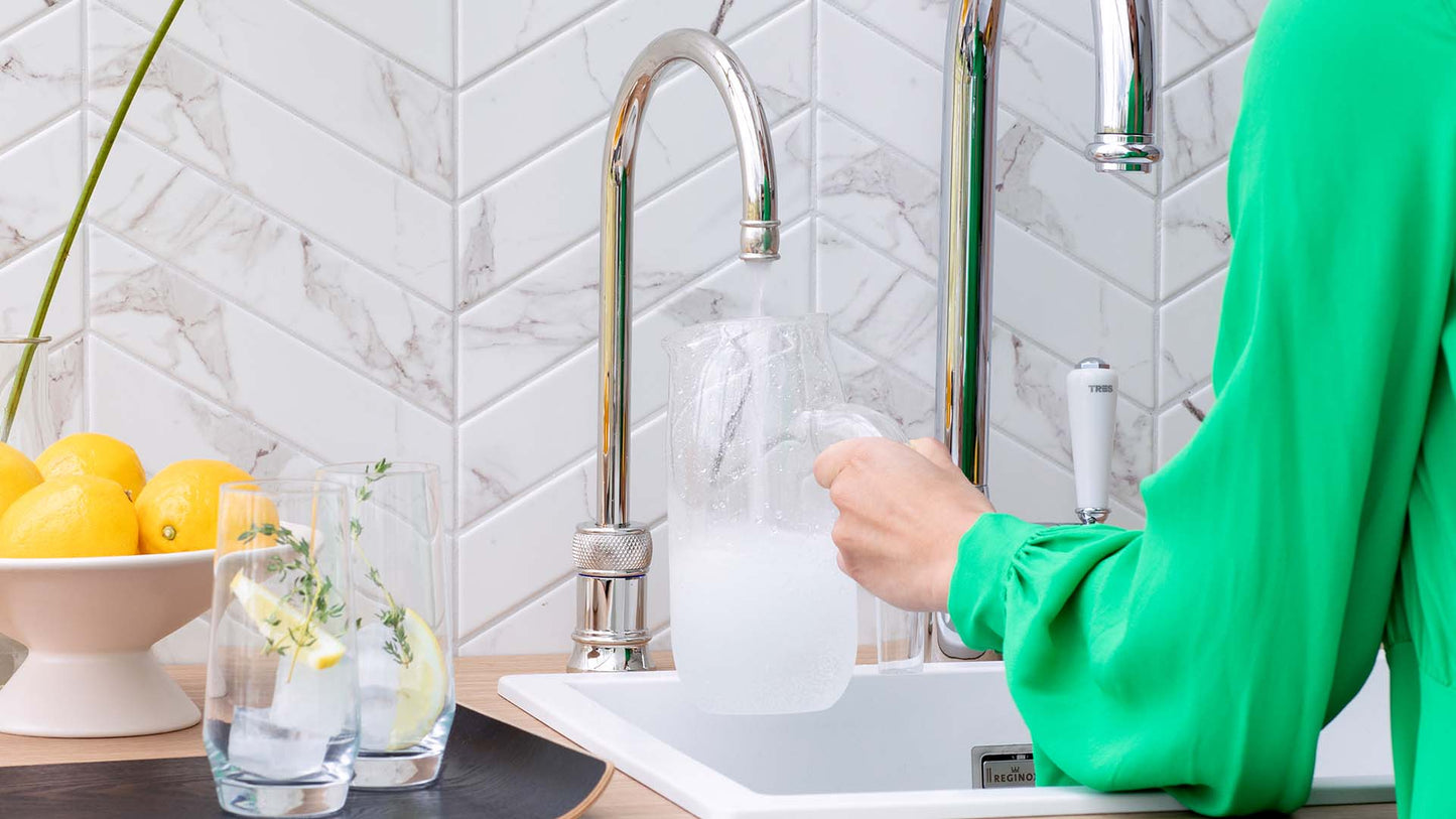 Helle Küchenzeile in Marmoroptik mit Wasserhahn mit kochendem Wasser im klassischen Design in Nickel mit rundem Auslauf und Kaltwasser.