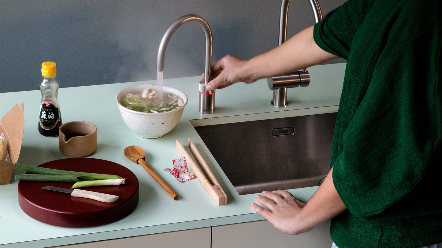 Helle Küchenzeile mit der Quooker Armatur in Voll-Edelstahl und geradem Auslauf als Kochend-Wasserhahn..