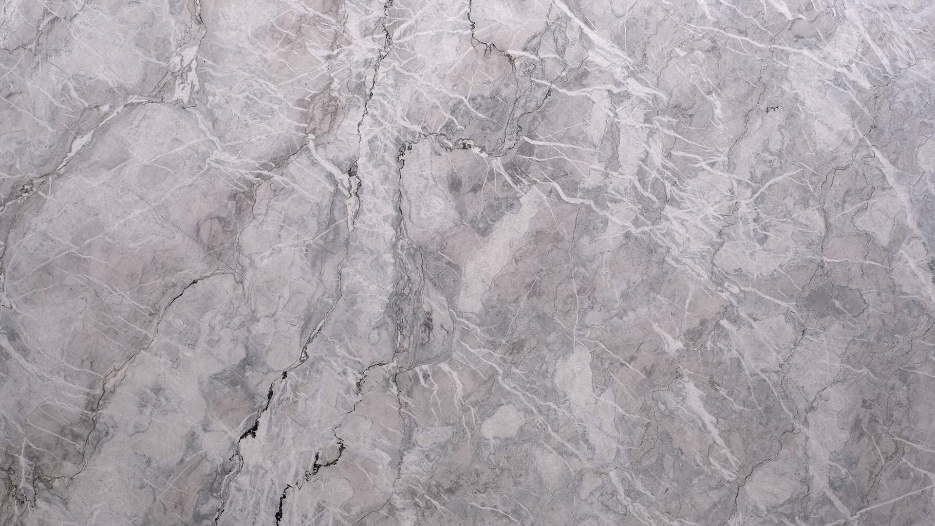 Naturstein Küchenarbeitsplatte in grau-weiss-schwarz mit starker Musterung, welche an Quellwolken erinnert und Partikel im Stein hat, welche glitzern.