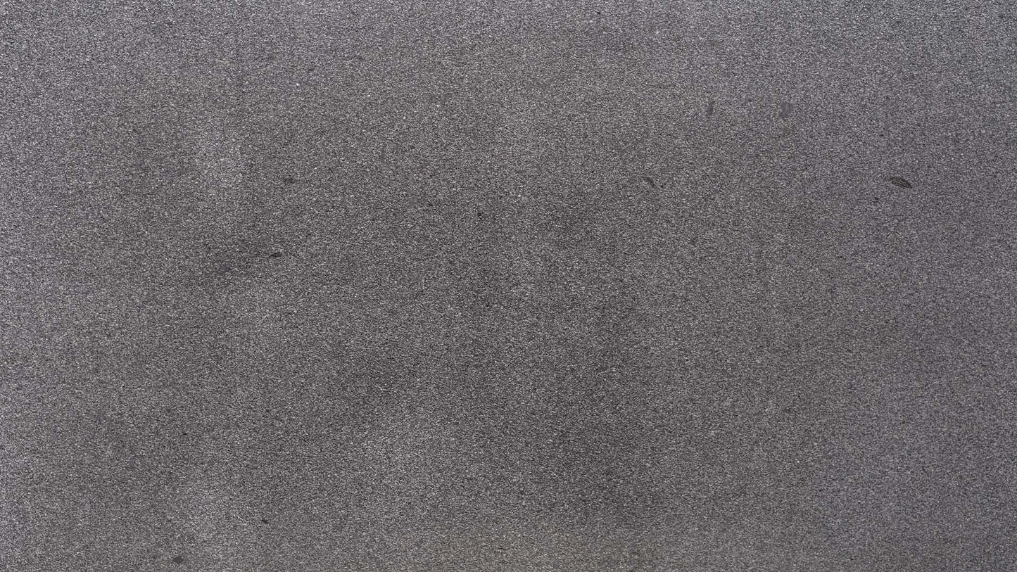 Naturstein Küchenarbeitsplatte in dunkelgrauer Grundfarbe mit weiss-schwarzen, feinen Sprenklern mit allgemein feiner Oberfläche in mattem leather Look in der Farbe Dunkelwalder.