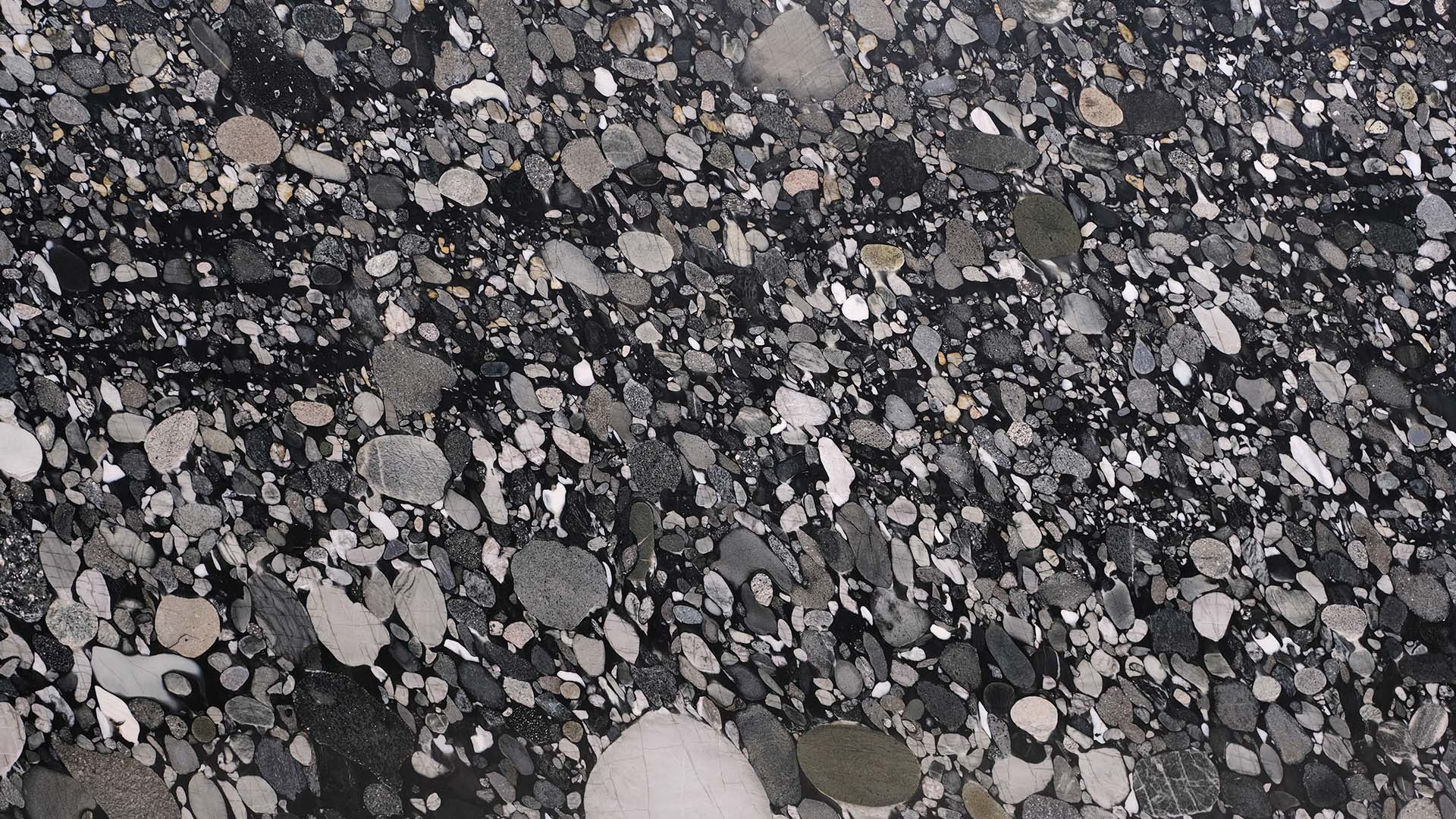Naturstein Küchenarbeitsplatte poliert in der Grundfarbe schwarz mit klar erkennbaren, einzelnen Steinen in den Farben grau und grün in der Farbe Nero Marinace.