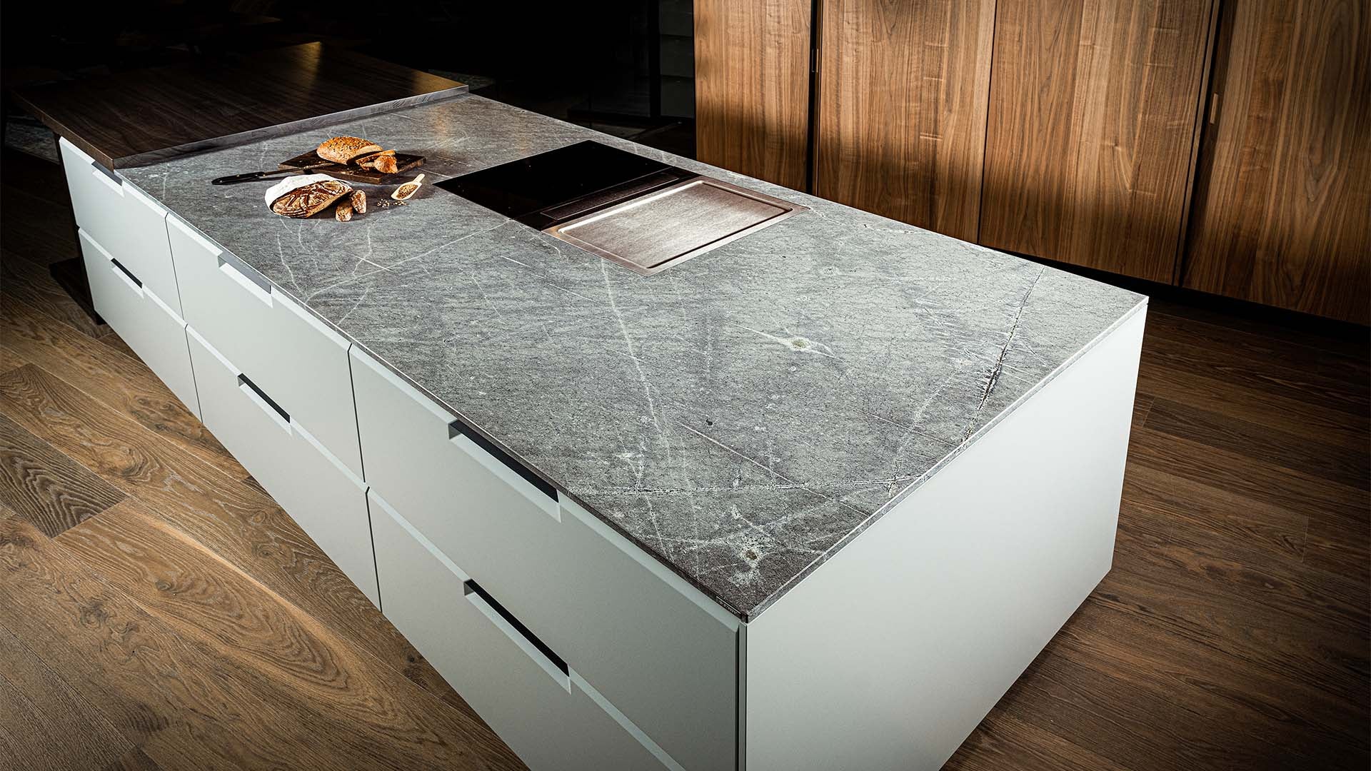 Weisser Küchenblock in Holzküche mit Naturstein Küchenarbeitsplatte in grua-grün semi-gloss in der Farbe Atlantis.
